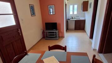 Un comedor con mesa y sillas, un televisor y una cocina al fondo.