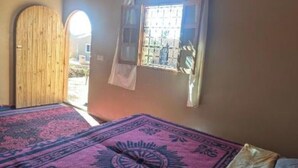 Un dormitorio con una cama, una ventana con cortinas, una puerta y un tapete estampado.