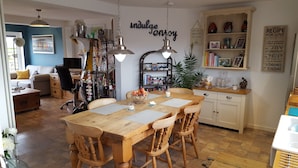 A cozy kitchen with a wooden table and chairs, a bookshelf, and a wall with motivational quotes. - B&B By The Sea (Lymington)