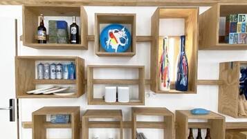 A wall of wooden shelves with various items including bottles, books, and decorative objects.