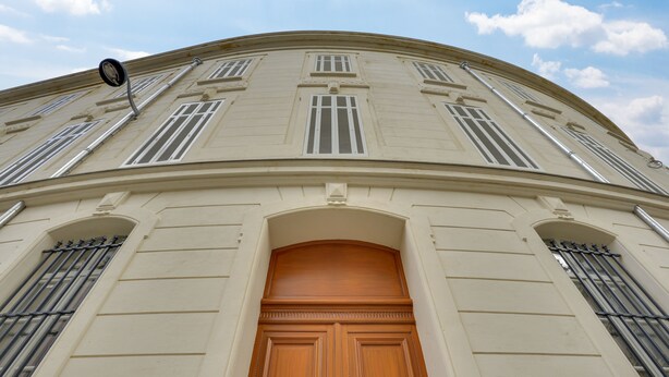 A classical building facade with symmetrical windows, a central wooden door, and a curved roofline. - The People - Marseille - Hostel (Marseille)