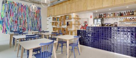 A modern interior with wooden cabinets, a bar area with bottles, and a colorful abstract art installation.