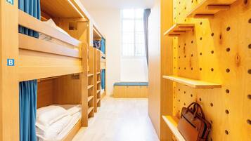 A bunk bed room with a wooden wall and a window.