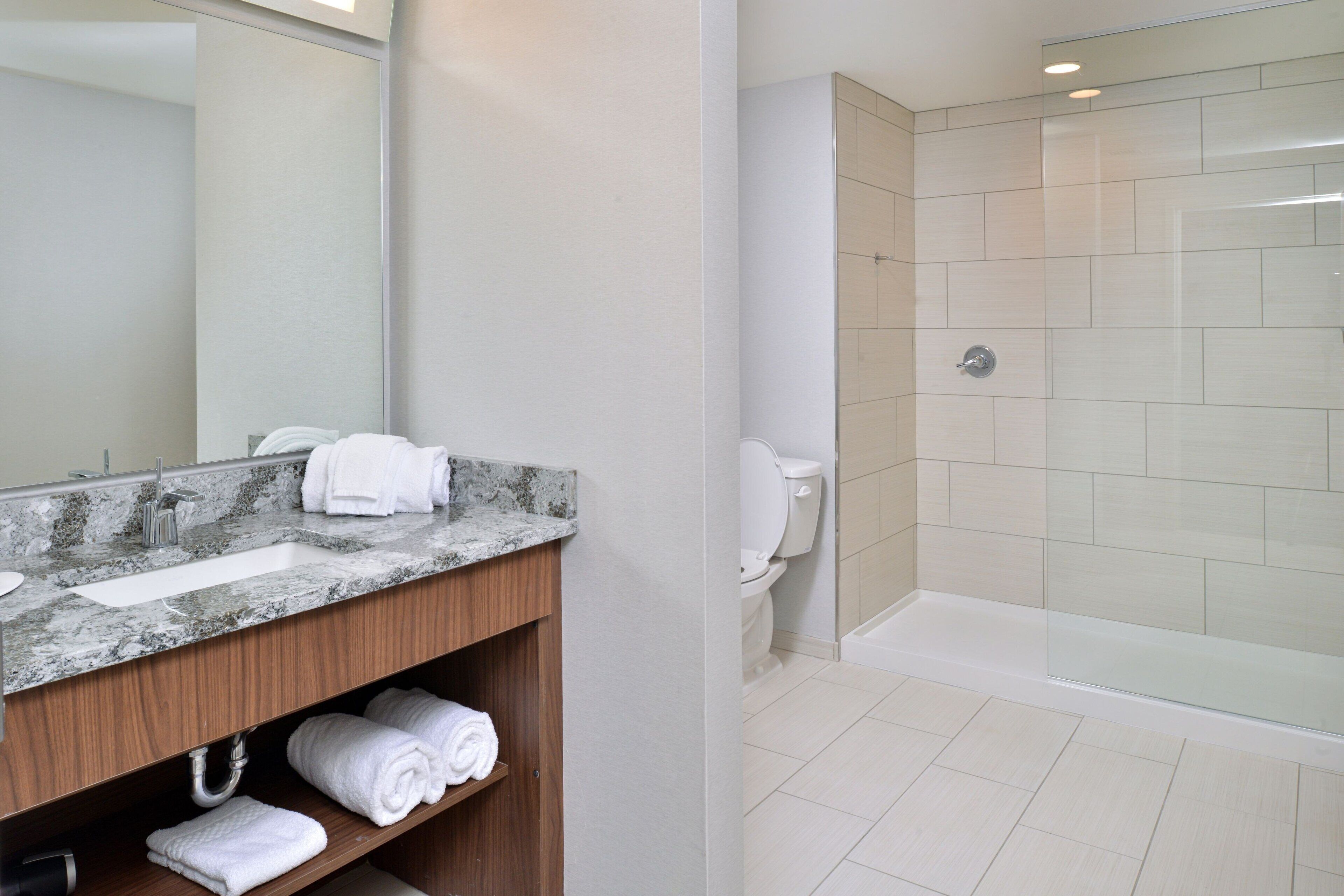 Un baño moderno con lavamanos de mármol, inodoro y ducha con cerramiento de vidrio.