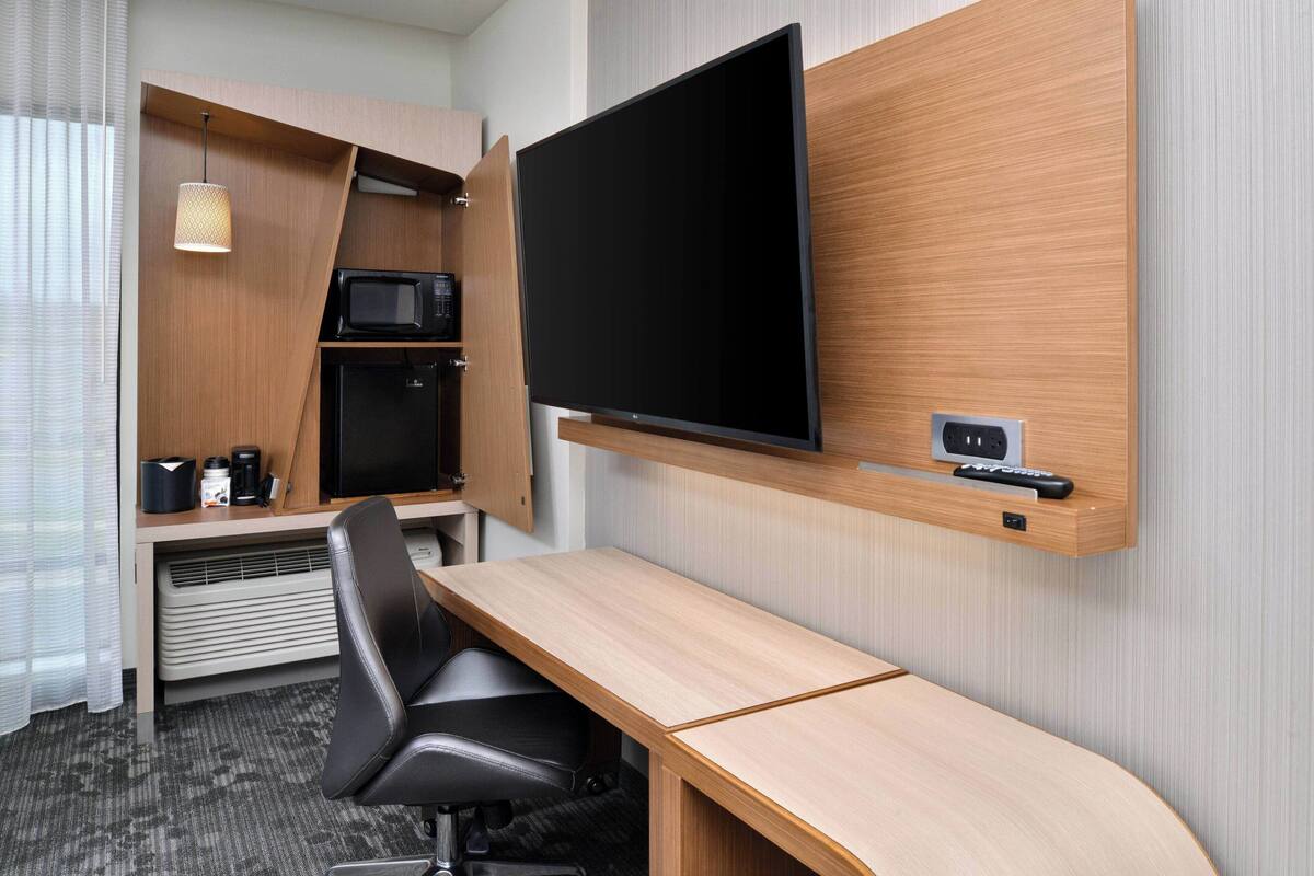 Een hotelkamer met een bureau, een flatscreen-tv, een magnetron en een koffiezetapparaat.