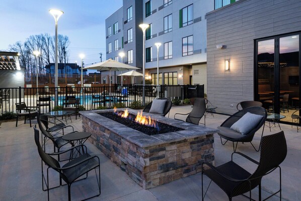 An outdoor patio area with a fire pit, seating, and a pool. - Courtyard by Marriott Charlotte Steele Creek (Charlotte)