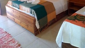 Un llit individual amb capçalera de fusta, una taula de nit i una petita taula auxiliar.