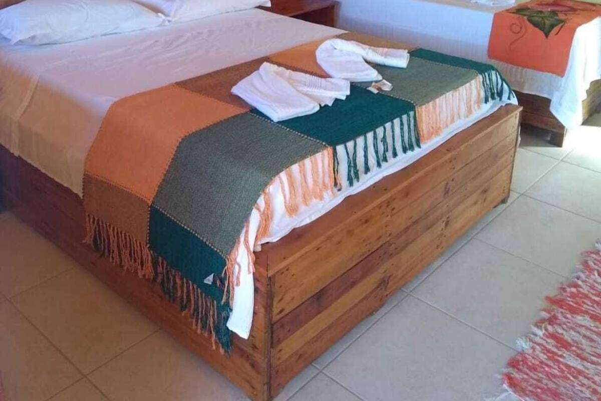 Una habitación con dos camas, cabecero de madera, suelo de baldosas y aire acondicionado instalado en la pared.