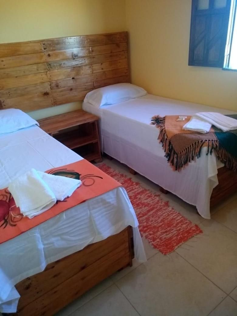 Une chambre avec deux lits, une tête de lit en bois et un tapis rouge.