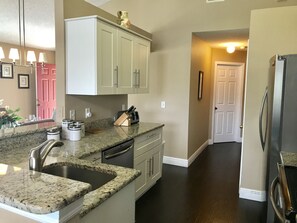 Kitchen features a dishwasher, double sink, and a small island with storage.