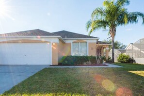 Standalone home with a garage and a well-maintained lawn, featuring a simple design and a small porch.
