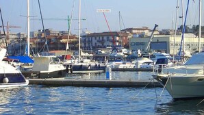 A marina with boats docked, a building labeled "CASA ROSINA" in the background, and a clear sky.