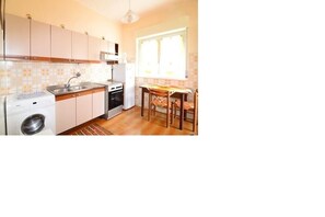 Cocina compacta con lavadora, estufa y comedor con mesa y sillas.