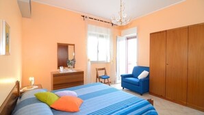 A bedroom with a bed, dresser, chair, wardrobe, and a window with curtains.