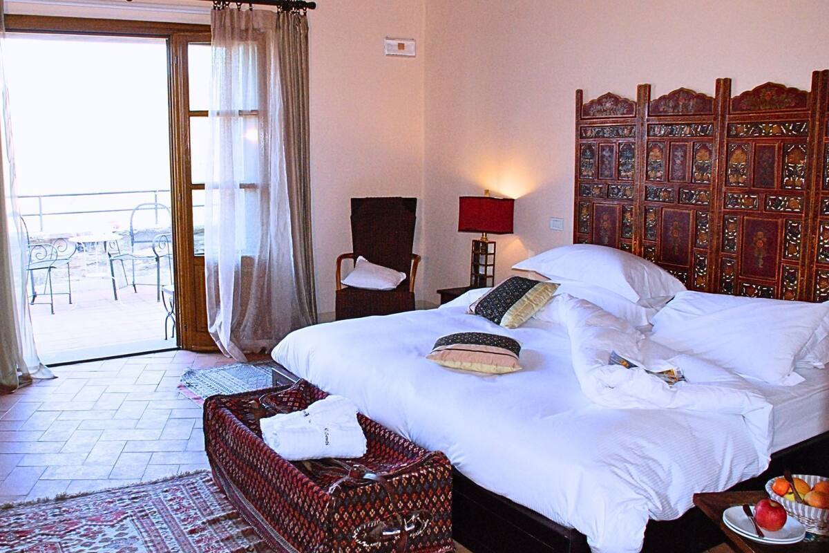 Habitación de hotel con cama, una silla, una mesa y vistas al exterior.