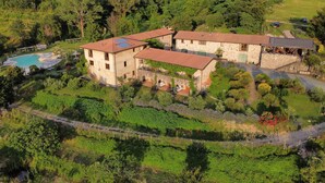 A large, rustic stone house with multiple rooms, a swimming pool, and lush gardens. - Podere Conti (Filattiera)