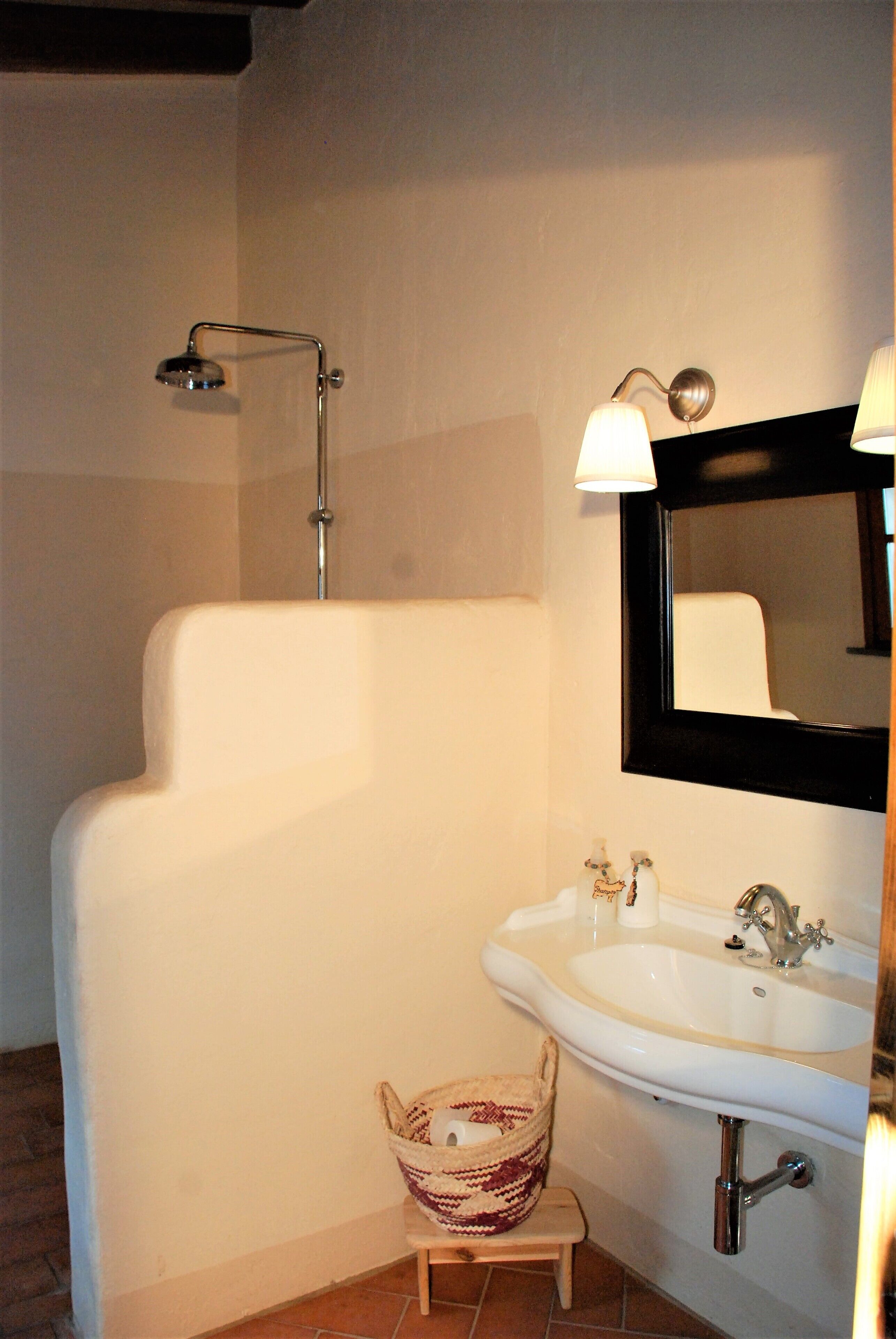 Een badkamer met een wit bad, een wastafel met spiegel en een douche.