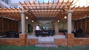 Un espace extérieur aménagé en terrasse, avec des bancs en briques et une pergola en bois.