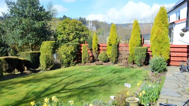 Un jardin bien entretenu, avec une pelouse, des haies taillées avec soin et une variété de plantes à fleurs.