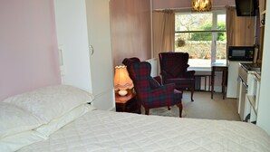 Une chambre avec un lit, un bureau et une chaise, une télévision et un four à micro-ondes.