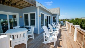 A covered deck with white Adirondack chairs and a table, overlooking a residential area. - Oceanside, Private Pool, Close to Beach, Hot Tub! SP2, Blew Bayou (Duck)