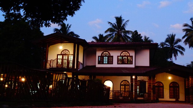 A two-story building with a balcony, arched windows, and a covered entrance.