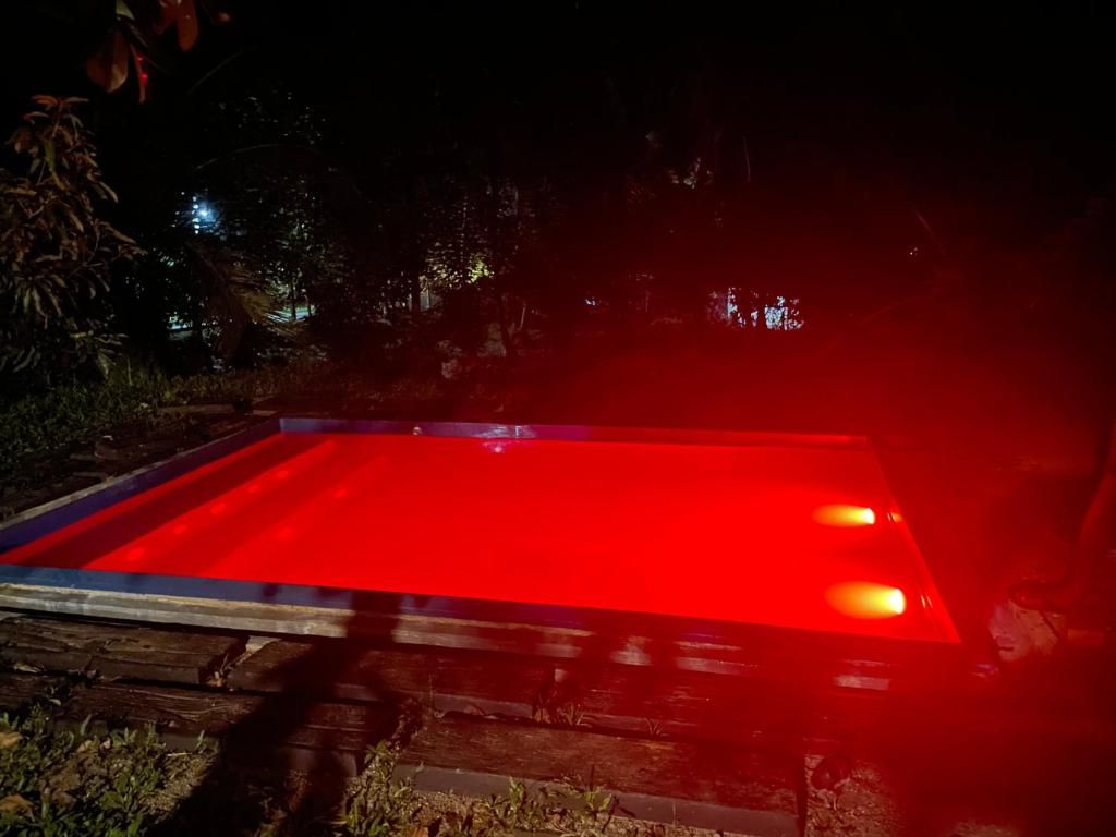 A rectangular pool with a red surface, surrounded by a wooden deck.