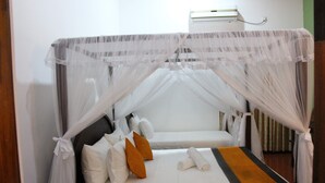 A bed with a canopy, pillows, and a towel.