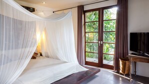 A bedroom with a bed, a TV, and a view of greenery through the window. - Rent a Luxury Villa in Bali Close to the Beach, Bali Villa 2035 (Bali)
