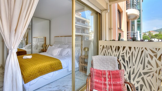 Ein Hotelzimmer mit Bett, Stuhl, einem Balkon und Blick sowie einer Wandverzierung.