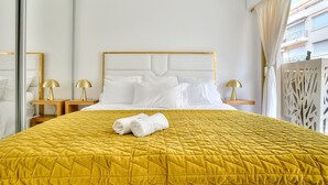 Ein Hotelzimmer mit einem großen Bett, zwei Nachttischen mit Lampen, einem weißen Kopfteil und Blick nach außen.