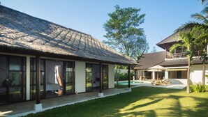 A modern resort with a thatched-roof structure, a pool area, and a well-maintained lawn.