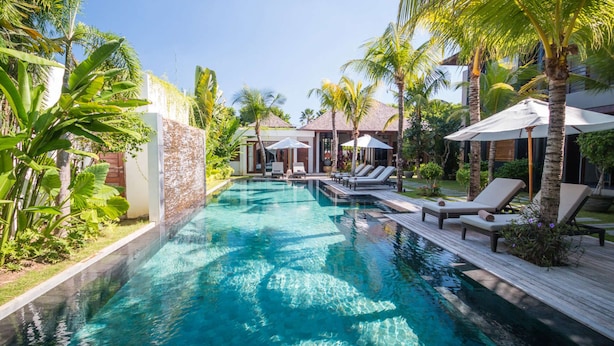 A pool with clear water, surrounded by palm trees and lounge chairs. - How to Rent Your Own Private Luxury Holiday Villa in Seminyak for Less than Basic Hotel (Bali)