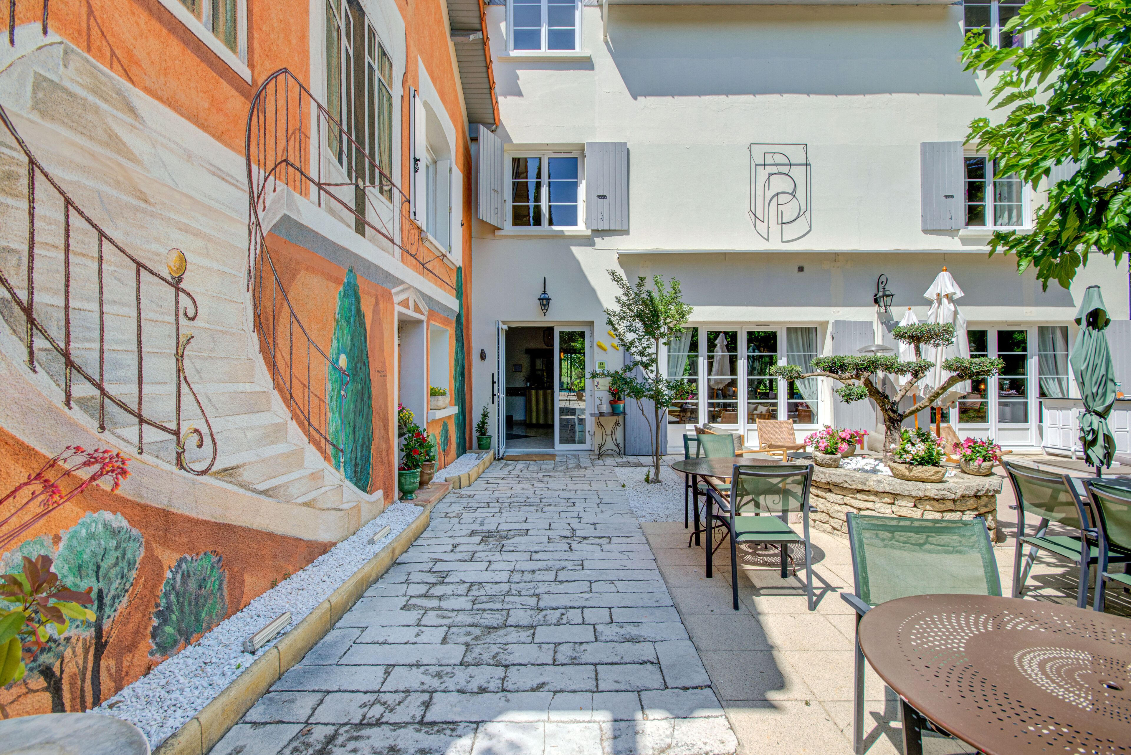 A courtyard with stone paving, outdoor seating, and potted plants.