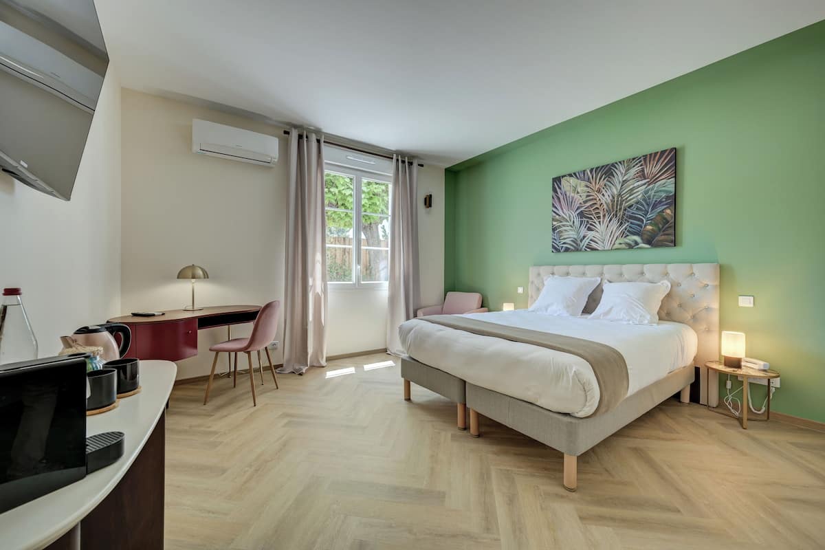 A hotel room with a bed, desk, chair, and a TV.