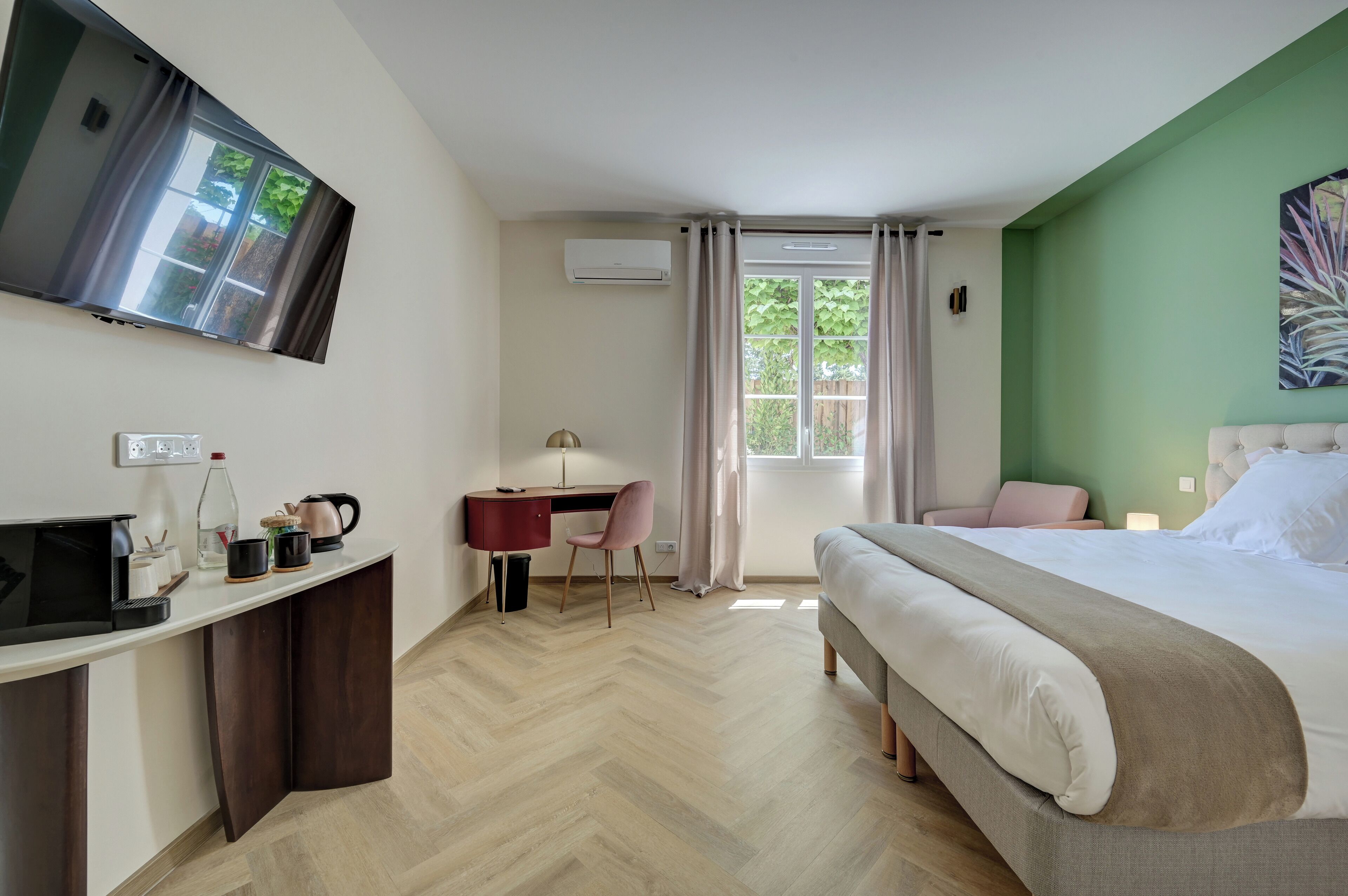 Ein Hotelzimmer mit Bett, Schreibtisch, Stuhl, Fernseher und einem Fenster mit Vorhängen.