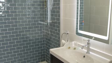 Une salle de bain avec une douche à parois de verre, un lavabo blanc et un miroir au-dessus.