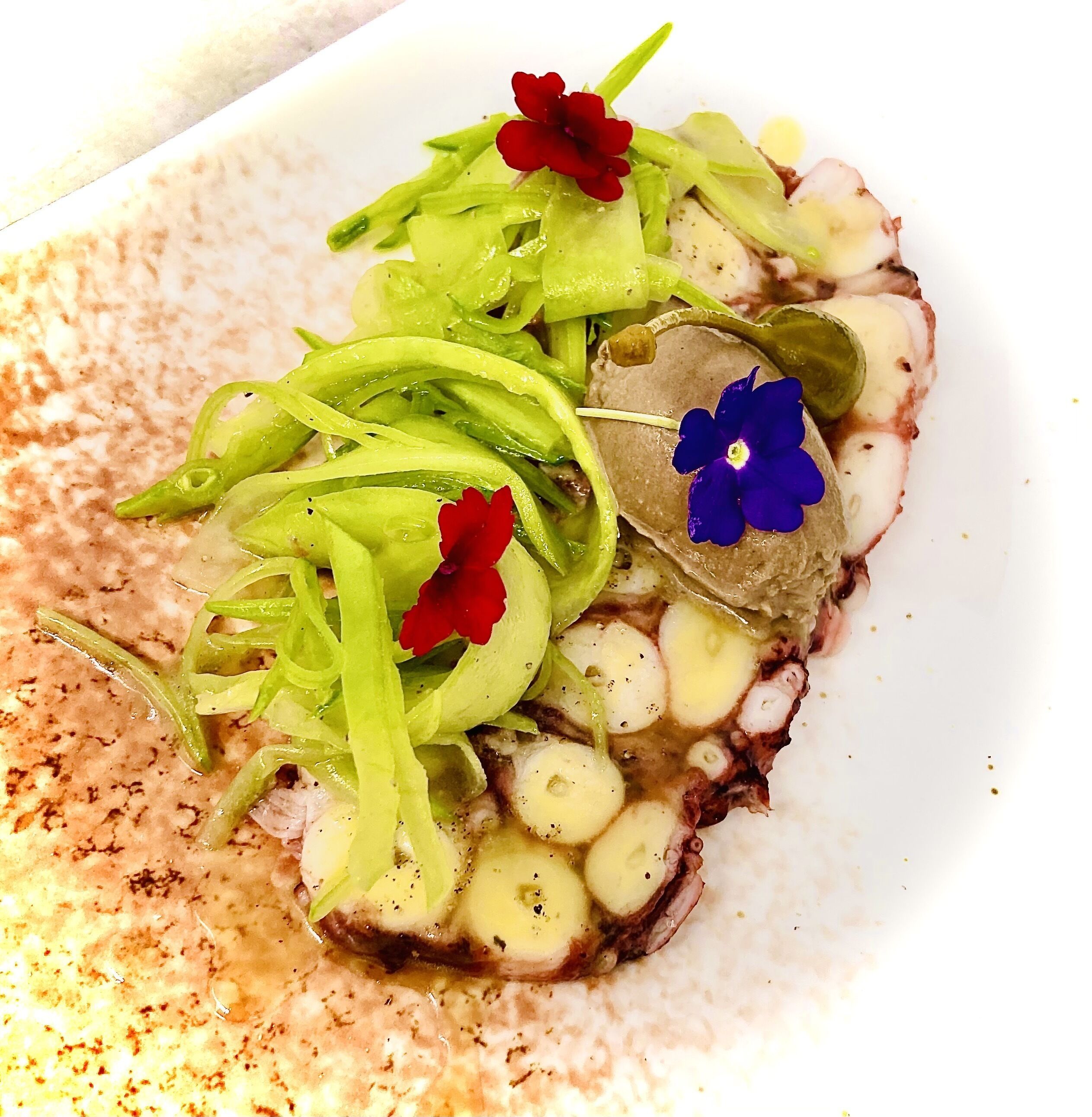 A plate of food with sliced meat, green vegetables, and flowers.
