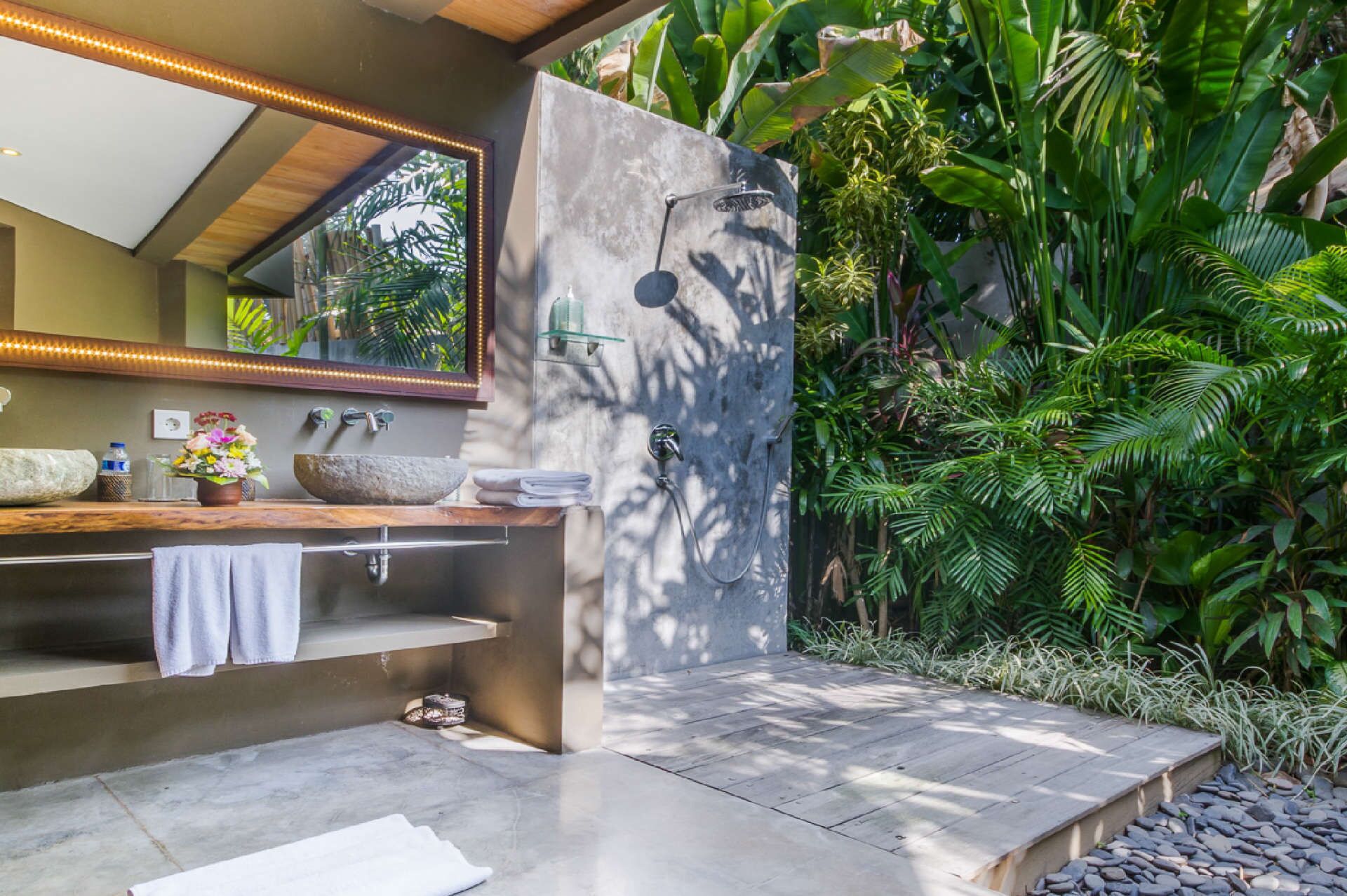 Un baño moderno con un lavabo de piedra, un espejo grande y una zona de ducha.