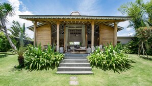 Una casa moderna con un porche cubierto, una escalera de piedra que conduce a la entrada y exuberante vegetación tropical.