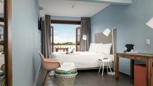 Una habitación de hotel con cama, escritorio, silla, una mesita y un cubo de basura.