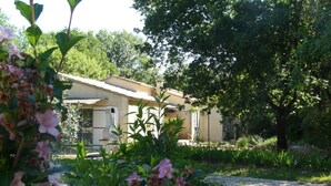 A rustic house with a garden in front, surrounded by trees. - --- GENEVRIER cottage --- (Quissac)