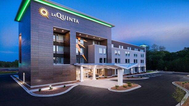 A modern hotel with a prominent 'LA QUINTA' sign, a covered entrance, and a parking lot. - La Quinta Inn & Ste by Wyndham Wisconsin Dells- Lake Delton (Wisconsin Dells)