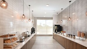 A modern kitchen with a long counter, built-in appliances, and hanging pendant lights. - La Quinta Inn & Ste by Wyndham Wisconsin Dells- Lake Delton (Wisconsin Dells)