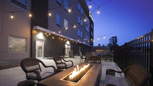 An outdoor seating area with a fire feature, chairs, and a building in the background. - La Quinta Inn & Ste by Wyndham Wisconsin Dells- Lake Delton (Wisconsin Dells)