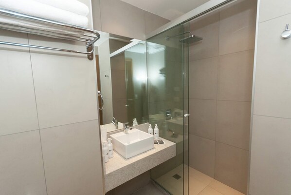Un baño moderno con cabina de ducha de vidrio, un lavabo blanco y un perchero para toallas.