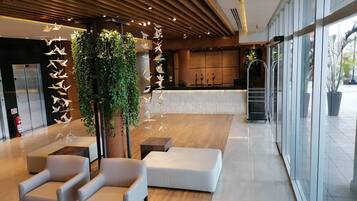 A modern lobby with a reception desk, seating area, and a large window offering a view of the outdoors.