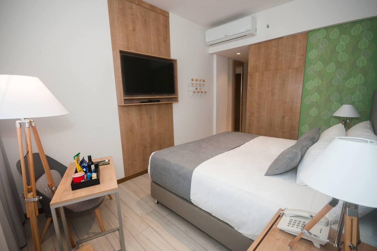 Ein Hotelzimmer mit Bett, Schreibtisch, Stuhl, Fernseher und Telefon.