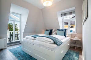 A bedroom with a bed, a window, a small table, and a chair.