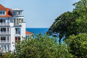 A multi-story building with balconies, a red-tiled roof, and a view of the sea. - App. Cardinal - cardinal (Kühlungsborn)